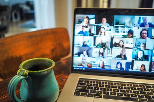 An open laptop shows a group video call on the screen